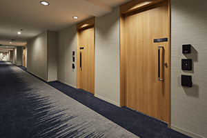 視力が低下しているお客様のご利用を考慮し、廊下とエレベーターホールのカーペットの配色に工夫を施し、はっきりとした濃淡を出すことで廊下と客室の境界線を現しています。